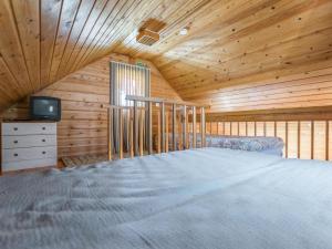 Cette chambre en bois comprend un grand lit et une télévision. dans l'établissement Holiday Home Tuomiranta by Interhome, à Pohjavaara