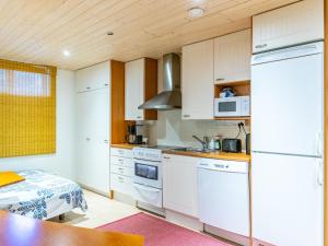 une cuisine avec des placards blancs et une table dans l'établissement Holiday Home Pispalan elokuvaranta by Interhome, à Tampere