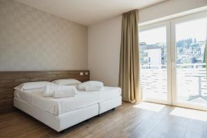 een slaapkamer met een wit bed en een groot raam bij Lake Side Suites in Riva del Garda