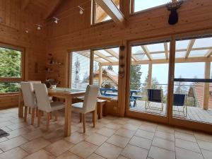 a dining room with a table and chairs and windows at Chalet Dolzer by Interhome in Hochrindl