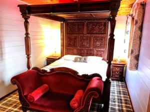 1 dormitorio con cama antigua y sofá rojo en Magpie 5 Hot Tub HuntersMoon-Warminster-Bath-Wiltshire en Warminster