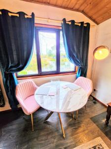 a dining room with a glass table and two pink chairs at Magpie 5 Hot Tub HuntersMoon-Warminster-Bath-Wiltshire in Warminster