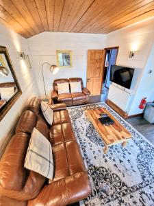 ein Wohnzimmer mit einem Ledersofa und einem Tisch in der Unterkunft Magpie 5 Hot Tub HuntersMoon-Warminster-Bath-Wiltshire in Warminster