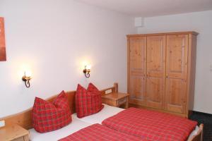 Schlafzimmer mit einem Bett mit roten Kissen und einem Schrank in der Unterkunft Appartement Hohe Mut in Obergurgl