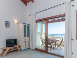 a living room with a television and a table with chairs at Apartment I Mirti 28 by Interhome in Porto Pozzo