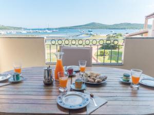 una mesa de madera con comida y bebida en el balcón en Apartment I Mirti 28 by Interhome, en Porto Pozzo