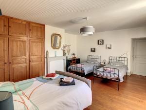 a bedroom with two beds in a room with wooden floors at Ferme Gascone proche Marciac in Bars