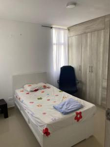 een slaapkamer met een bed en een blauwe stoel bij APARTAMENTO ALAMEDA DEL RIO in Barranquilla