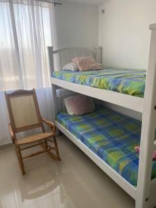 een slaapkamer met 2 stapelbedden en een stoel bij APARTAMENTO ALAMEDA DEL RIO in Barranquilla