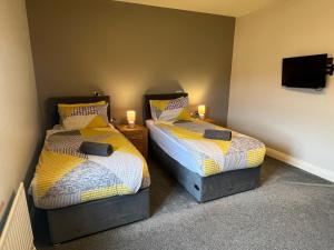 two twin beds in a room with a tv at 2 Castle Hume Court Holiday House in Enniskillen