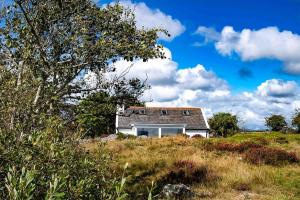 ein kleines weißes Haus auf einem Hügel auf einem Feld in der Unterkunft Gemütliches Cottage mit Meerblick in Ballydehob