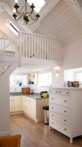a kitchen with white cabinets and a white staircase at Gemütliches Cottage mit Meerblick in Béal an dá Chab