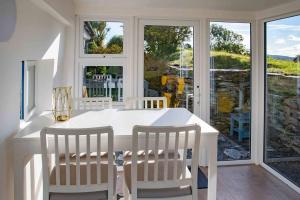 ein weißes Esszimmer mit einem weißen Tisch und Stühlen in der Unterkunft Gemütliches Cottage mit Meerblick in Ballydehob