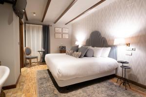 um quarto com uma grande cama branca num quarto em Hotel Cetina Palacio de los Salcedo em Baeza