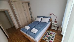 een slaapkamer met een bed met blauwe lakens en witte kussens bij Apartman Centar Bečej in Bečej
