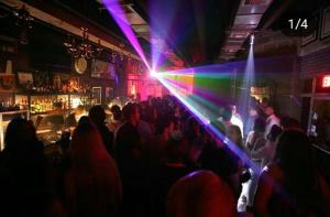 a crowd of people in a bar with lasers at Suites By SalcedO in Santo Domingo