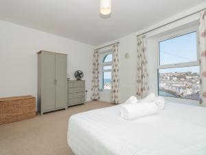 a bedroom with a white bed and a large window at 2 North Furzeham Road in Brixham