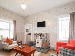 a living room with a fireplace and a tv on the wall at Station House in Lybster