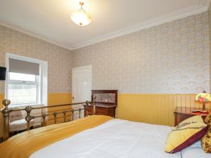 1 dormitorio con 1 cama con papel pintado de color amarillo y azul en Station House en Lybster
