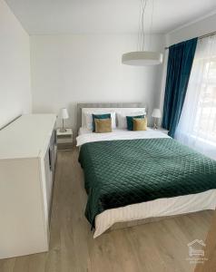 a bedroom with a large bed with a green blanket at Apartamentai Biržuose, Cozy Modern Bungalows in Biržai
