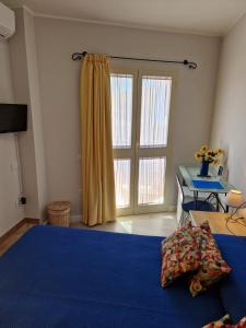 a bedroom with a blue bed and a large window at Ca'Mea in Villasimius