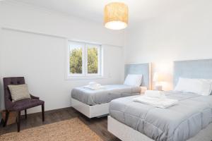 a bedroom with two beds and a chair and a window at Cascais Duplex Apartment in Cascais