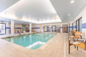 a large pool in a hotel with chairs and tables at Courtyard Burlington Williston in Burlington