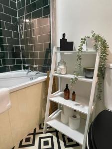 a bathroom with a white shelf with plants and a tub at Hoole House- Recently decorated, bright and modern 2 bedroom house, close to Chester train station and the City Centre in Chester +20 photos