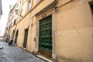 une porte verte sur le côté du bâtiment dans l'établissement suity I cozy leutari 23, à Rome