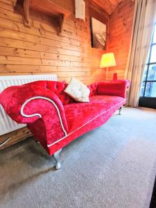 ein rotes Sofa in einem Zimmer mit einer Holzwand in der Unterkunft Otter 4 Hot Tub - HuntersMoon-Warminster-Bath-Salisbury in Warminster
