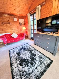 ein Wohnzimmer mit einem roten Sofa und einem TV in der Unterkunft Otter 4 Hot Tub - HuntersMoon-Warminster-Bath-Salisbury in Warminster