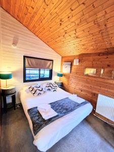 ein Schlafzimmer mit einem großen Bett in einem Holzzimmer in der Unterkunft Otter 4 Hot Tub - HuntersMoon-Warminster-Bath-Salisbury in Warminster