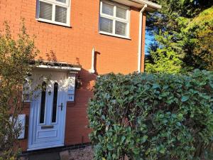 a brick house with a white door and a bush at 2 Bedroom end of terrace house in Wellington