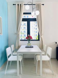 a white dining room table with white chairs and a window at Sea&CityView 2-bedroom Fully Furnished Apartment Forest City #freeWIFI in Gelang Patah