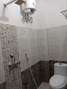baño con aseo y una luz en la pared en The A Cube Inn, en Bokāro