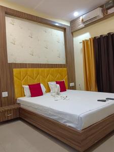 1 dormitorio con 1 cama grande con almohadas rojas y amarillas en The A Cube Inn, en Bokāro