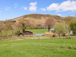 un campo con una valla y una colina al fondo en Whiteside, en Cockermouth