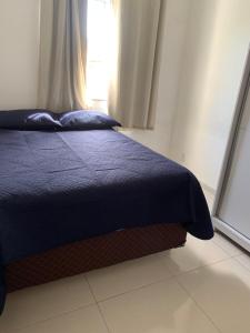 um quarto com uma cama azul e uma janela em Apartamento completo Ilheus em Ilhéus