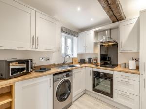 a kitchen with white cabinets and a washer and dryer at Barn One in Sandbach