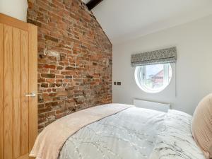 a bedroom with a brick wall and a bed at Barn One in Sandbach