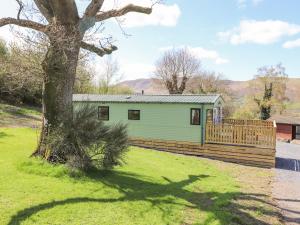 a green house with a wooden fence and a tree at Swinside in Cockermouth