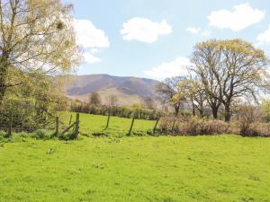 a field with a fence and mountains in the background at Swinside in Cockermouth