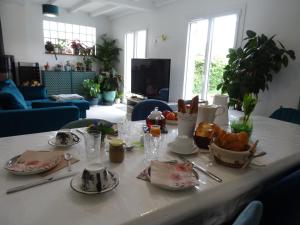 una mesa blanca con comida en la sala de estar en Maison d'hôtes les roses trémières, en Saclay