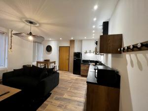a living room with a black couch and a kitchen at Appartement cosy centre ville in Roanne