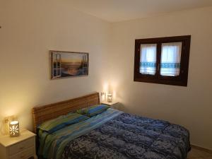サン・パスクアーレにあるAppartamento Costa Smeraldaのベッドルーム1室(ベッド1台、窓2つ付)
