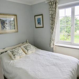 a bedroom with a white bed with pillows and a window at Newmans Lodge in Lavenham