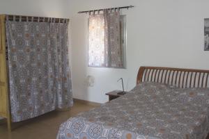 Schlafzimmer mit einem Bett und einem Fenster mit Vorhängen in der Unterkunft Le Margouillat 