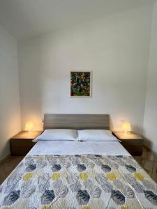 a bedroom with a bed with two nightstands and a painting at Appartamento La Conchiglia a pochi passi dal centro in San Teodoro