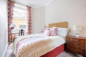 a bedroom with a bed with a wooden dresser and a window at Charming flat in quiet street in Stockbridge in Edinburgh