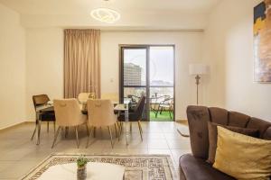 a living room with a couch and a table and chairs at Leen Homes-JBR -Spacious 4 Bedroom apartment in Dubai